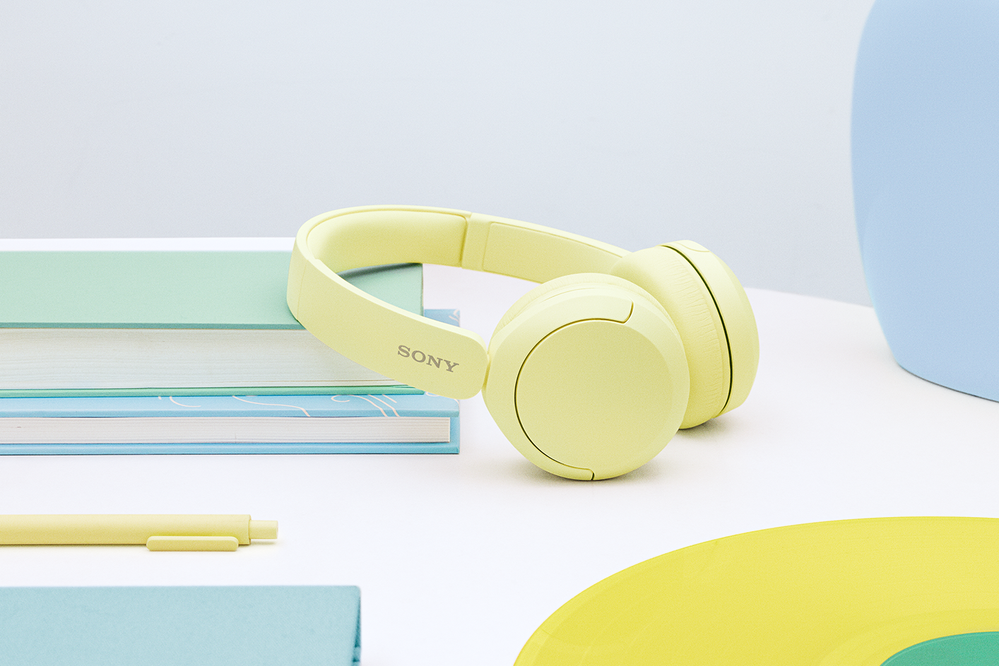 A pair of yellow Sony WH-CH520 headphones on a desk.