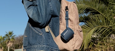 Image of the XB13 EXTRA BASS(TM) Portable Wireless Speaker attached to a young woman's backpack.