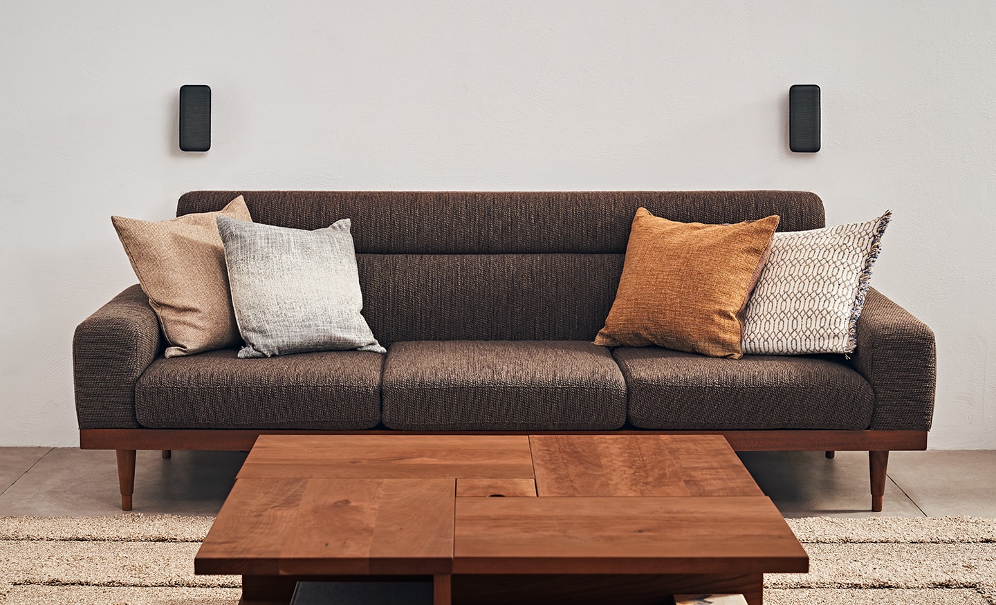 A sofa with the wireless satellite speakers behind